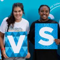 four students posing in front of CAB backdrop at Laker Kickoff photo booth holding GVSU letters
